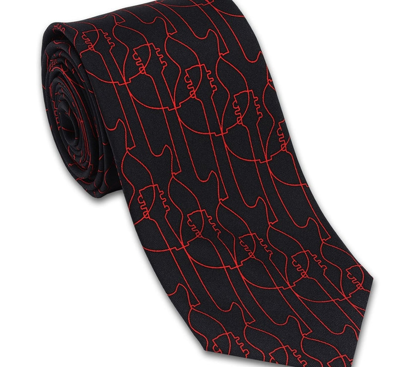 A silk necktie with a pattern of red guitars on a black background, rolled up presumably for packaging.