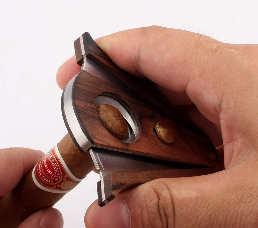 Hand holding a wooden cigar cutter with a cigar on a white background
