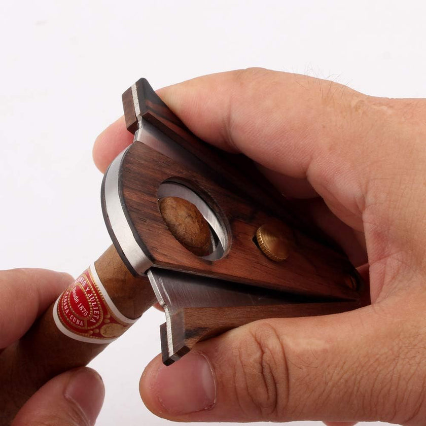 Hand holding a wooden cigar cutter with a cigar on a white background