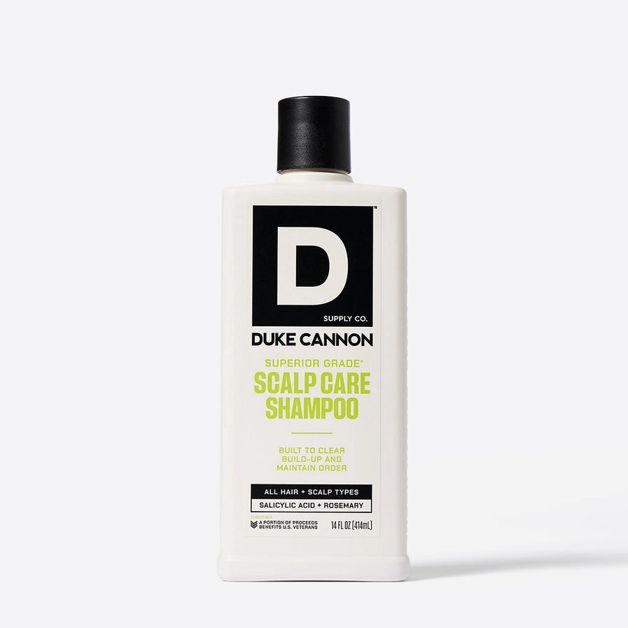 A bottle of Duke Cannon Superior Grade Scalp Care Shampoo with white and green labeling, featuring salicylic acid and rosemary.