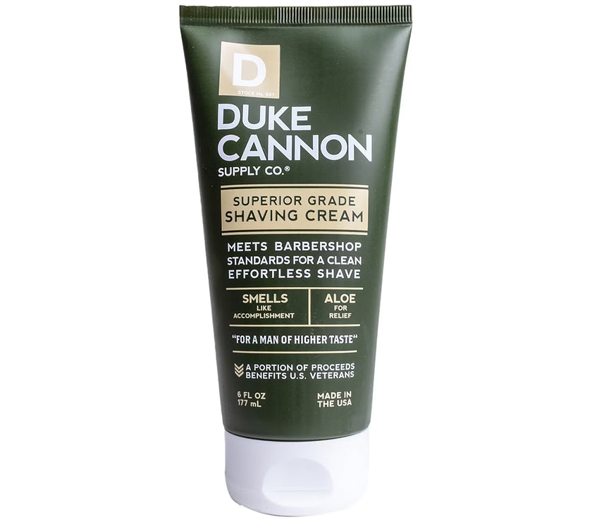 A tube of Duke Cannon Superior Grade Shaving Cream with green and white packaging.