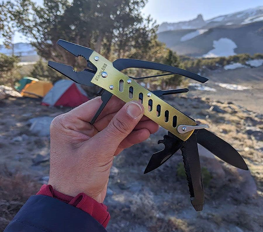 Multitool held in a hand with a mountainous landscape in the background
