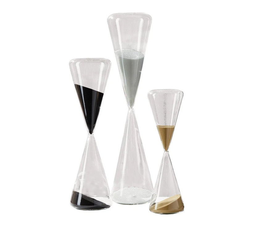 Set of three hourglass-shaped glass containers with different color sand on a white background