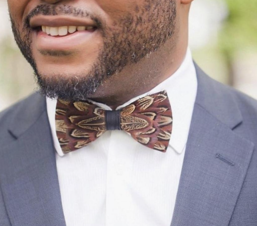 A man wearing a handmade brown feather bow tie.
