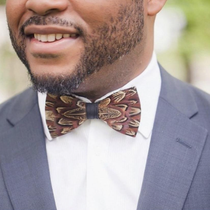 A man wearing a handmade brown feather bow tie.