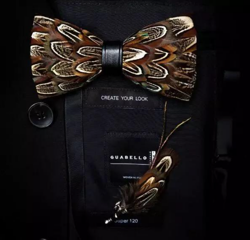 A handmade brown feather bow tie on top of a bag that says "create your look" with another feather accent below.