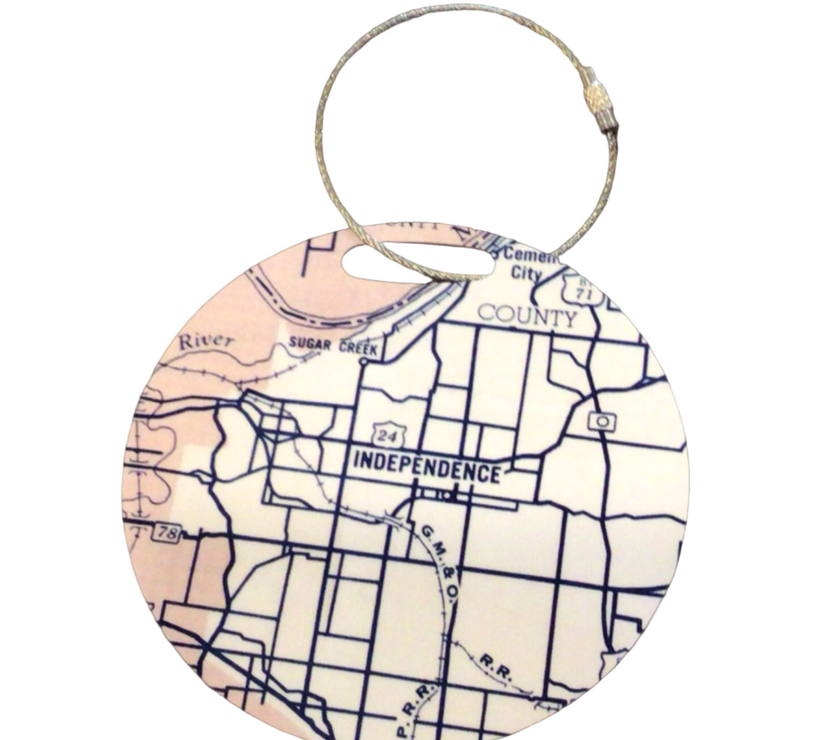A round luggage tag with a map of Independence, Missouri on it, attached to a durable cable attachment.