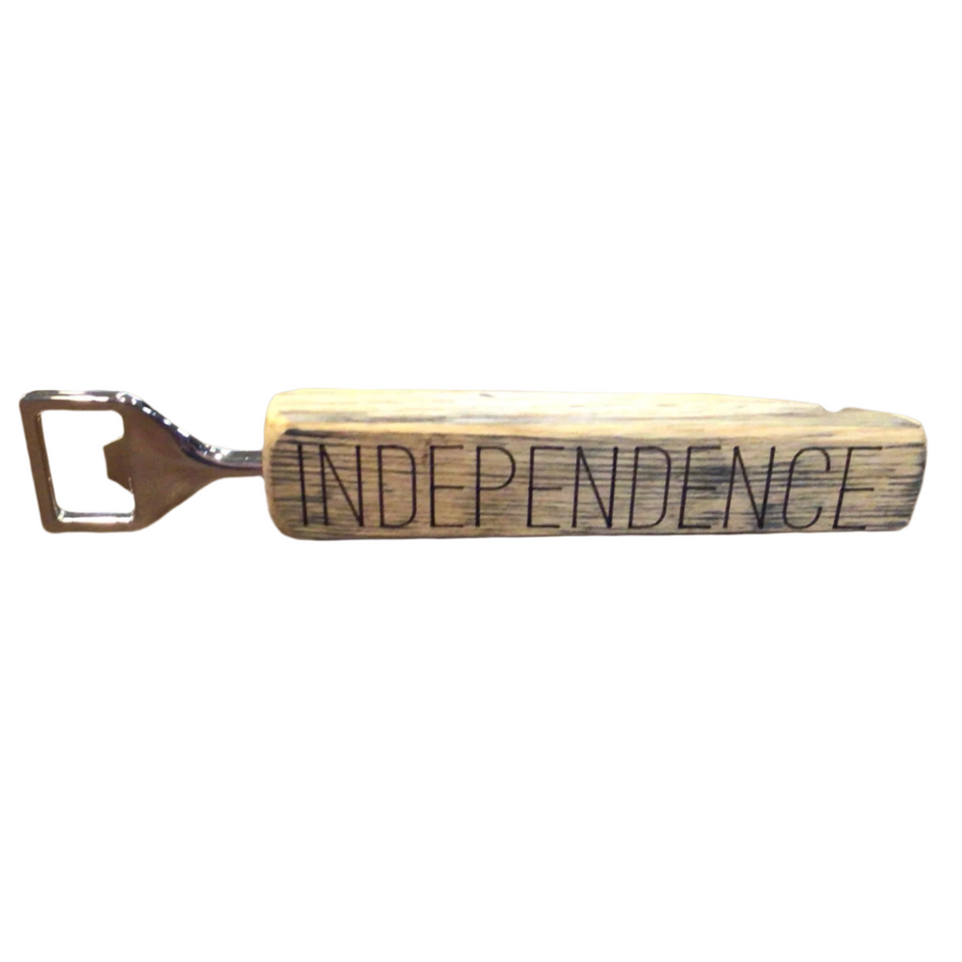 A wooden bottle opener with the engraved text 'INDEPENDENCE' on the handle.