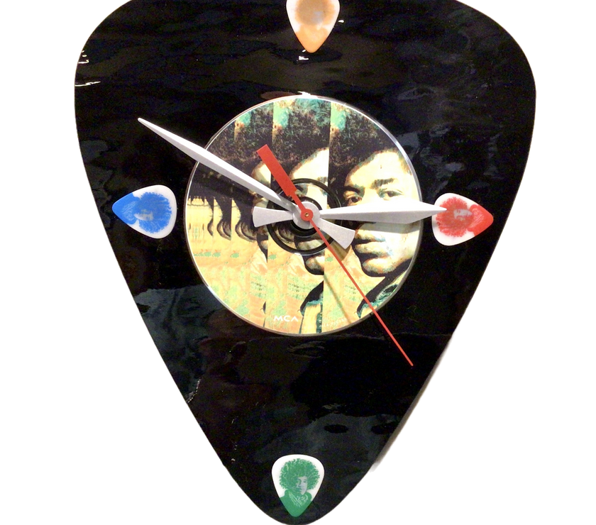 A decorative wall clock featuring a colorful image of a guitar and a portrait of Jimi Hendrix, with a black background and colorful accents.