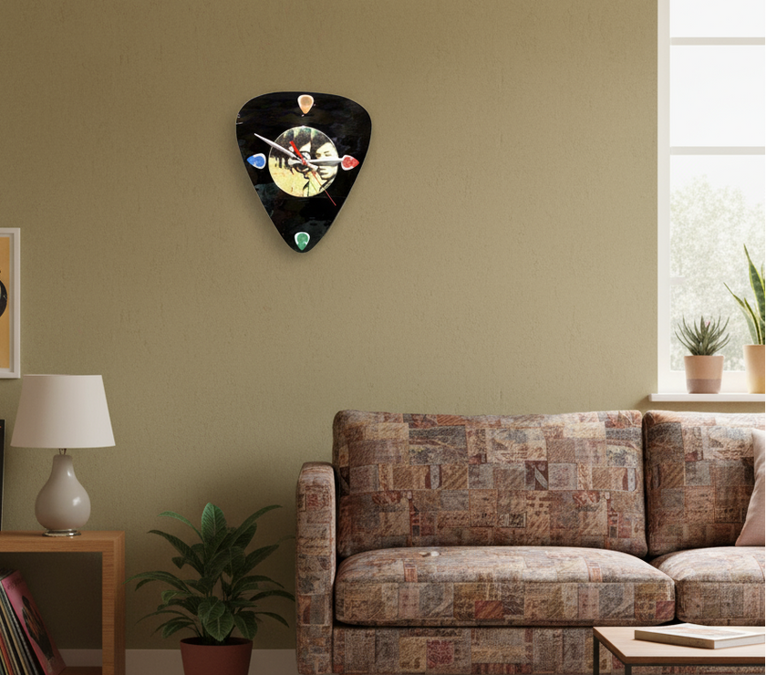 Living room with a guitar pick-shaped clock on the wall, a couch, and a shelf with books and a lamp.
