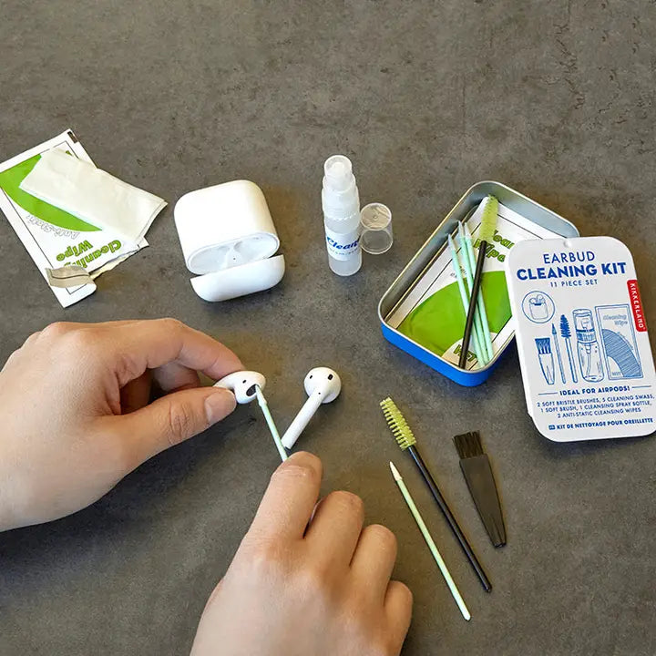 Earbud cleaning kit with earbuds, brush, and tools on a gray surface