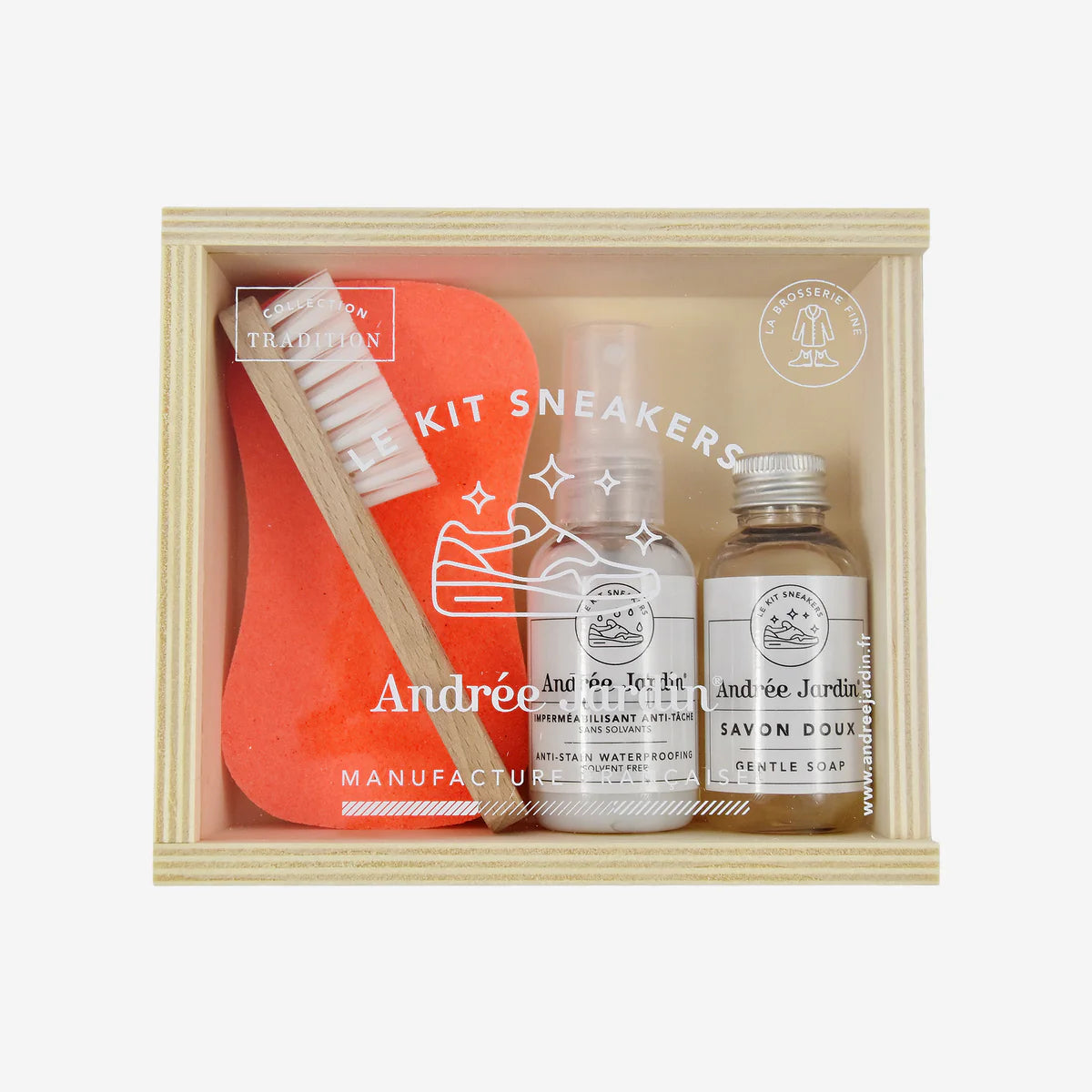 Shoe cleaning kit with a brush, bottle, and jar in a wooden box on a white background