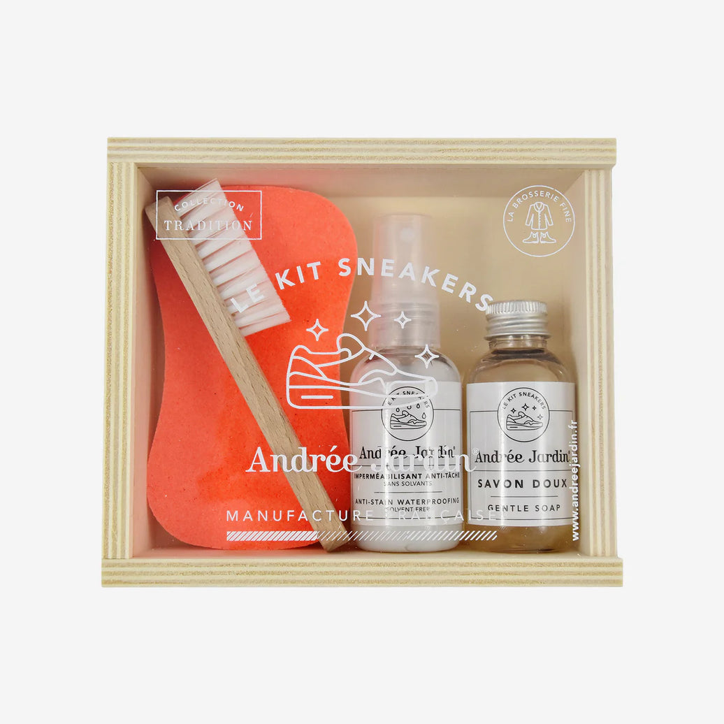 Shoe cleaning kit with a brush, bottle, and jar in a wooden box on a white background