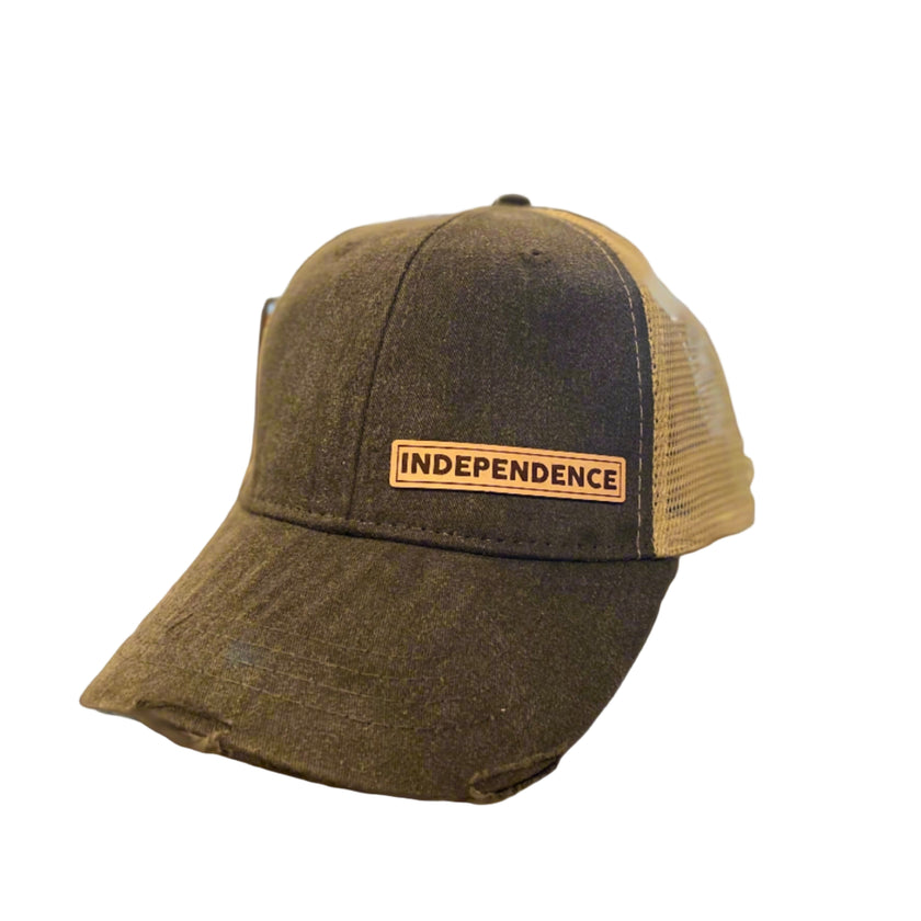 A black vintage-colored ball cap with a beige mesh and a leather patch on the front that reads 'INDEPENDENCE'.