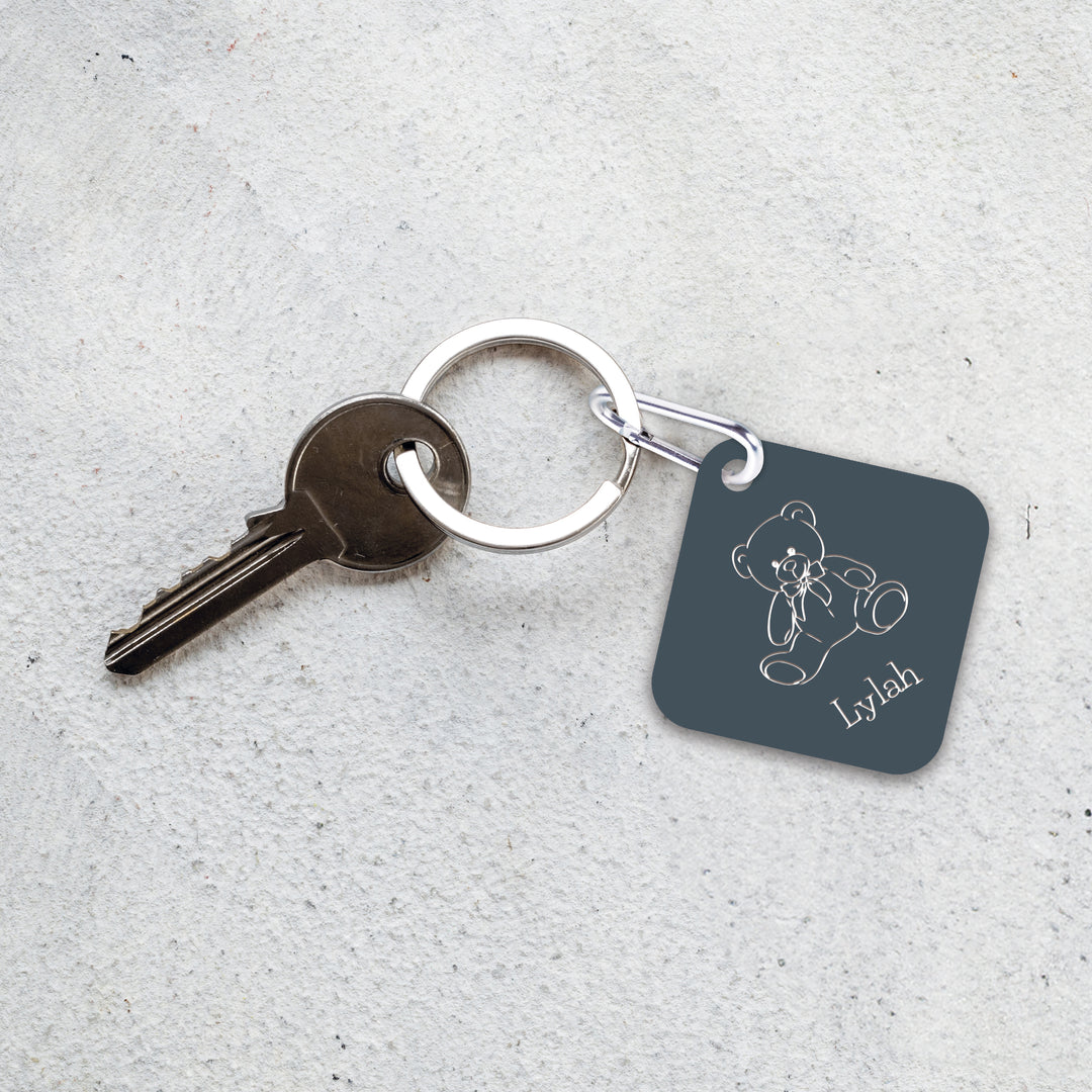 An engraved blue-gray luggage tag/keychain on a keyring with a key.