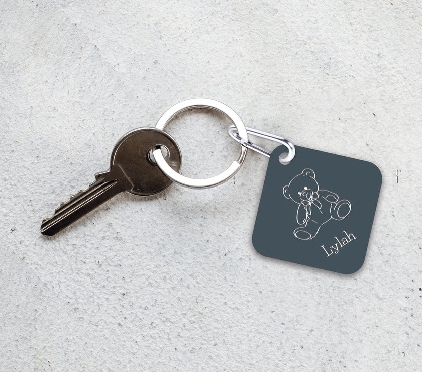 An engraved blue-gray luggage tag/keychain on a keyring with a key.