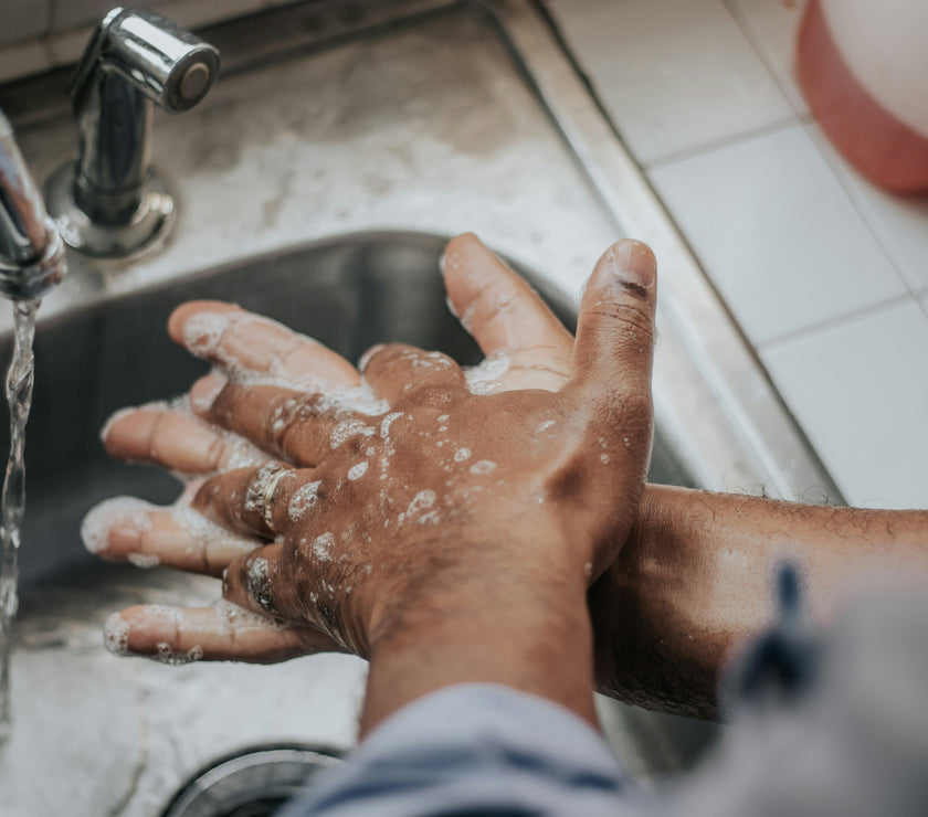 Person washing hands under running water in a sink.