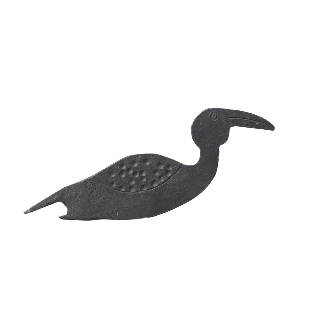 A metal bottle opener in the shape of a bird with a long beak.