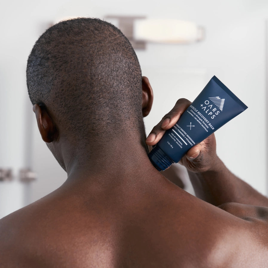 A man using the Oars + Alps Muscle Recovery Balm on his neck.