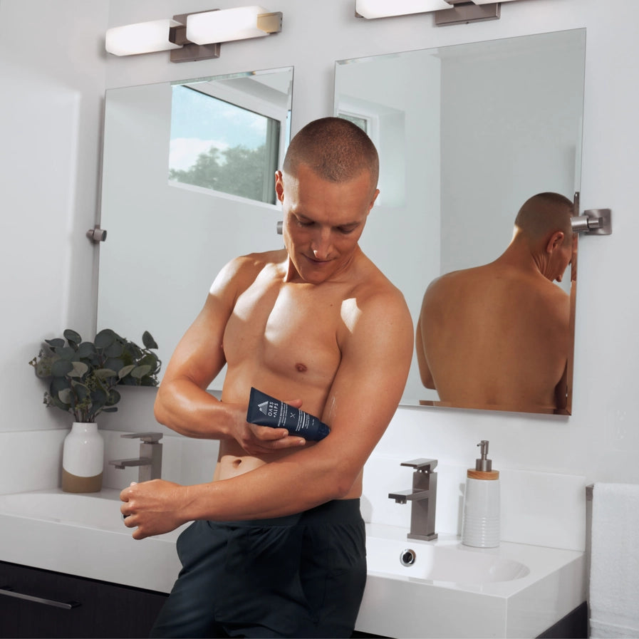 A man using Oars + Alps muscle recovery balms on his arm.