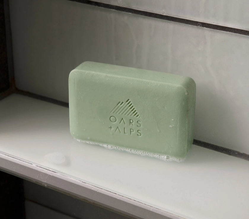 A bar of Oars and Alps Epsom Salt soap sitting on a white shelf.