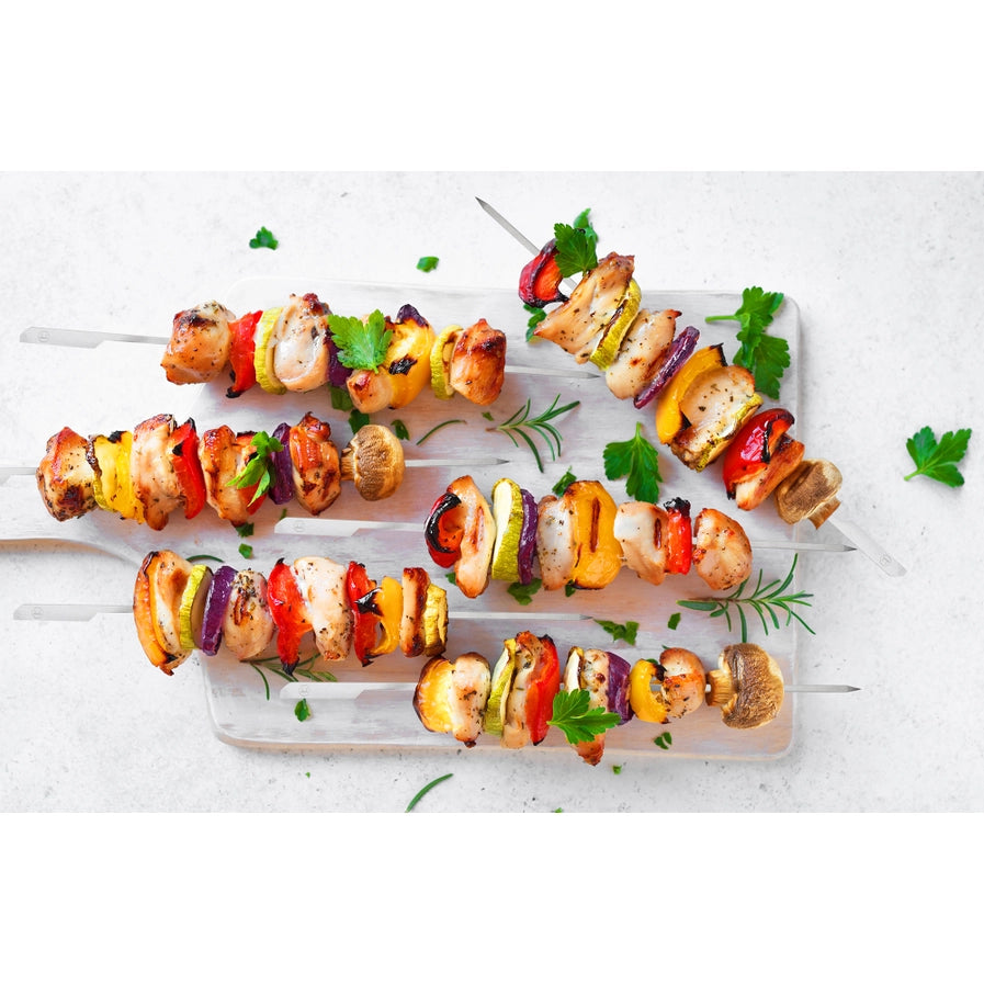 Colorful skewers with grilled vegetables and chicken on a white surface.