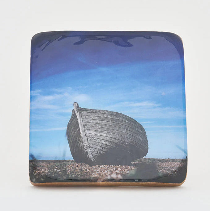 A decorative item featuring a black and white image of a beached traditional fishing boat on a wooden block.