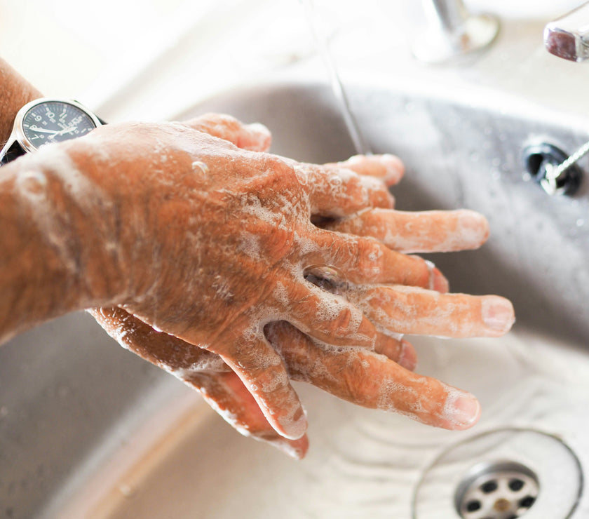 Person washing hands with soap under running water in a sink