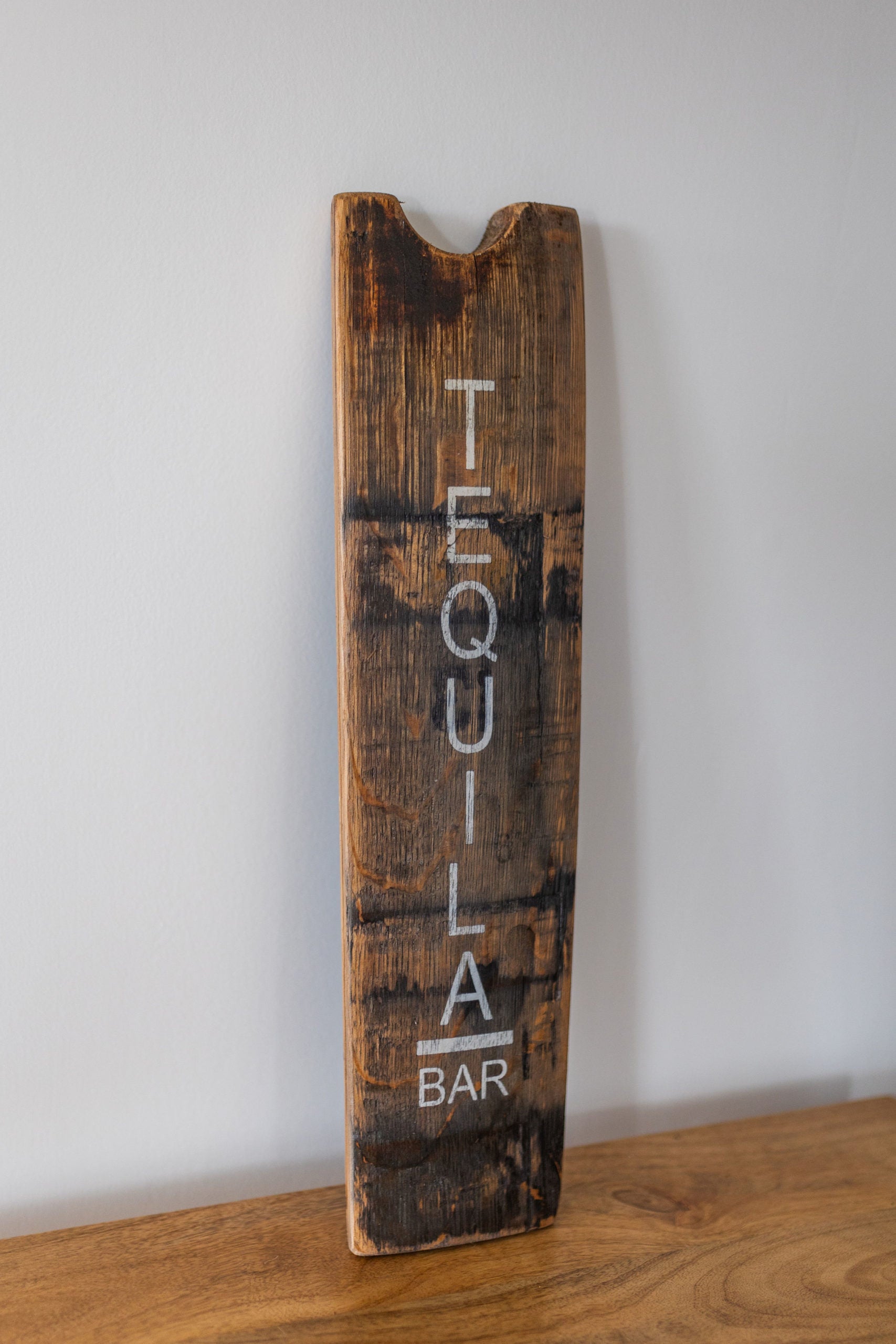 Wooden sign with 'Tequila Bar' text on a white wall