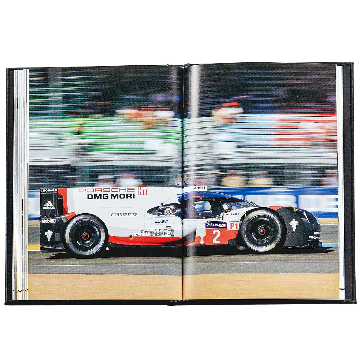 An inside look at a book titled The Story of Porsche open to a full two-page spread of a racing Porsche car.
