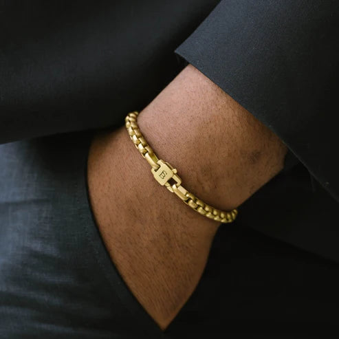 Gold bracelet on a wrist with a dark suit background