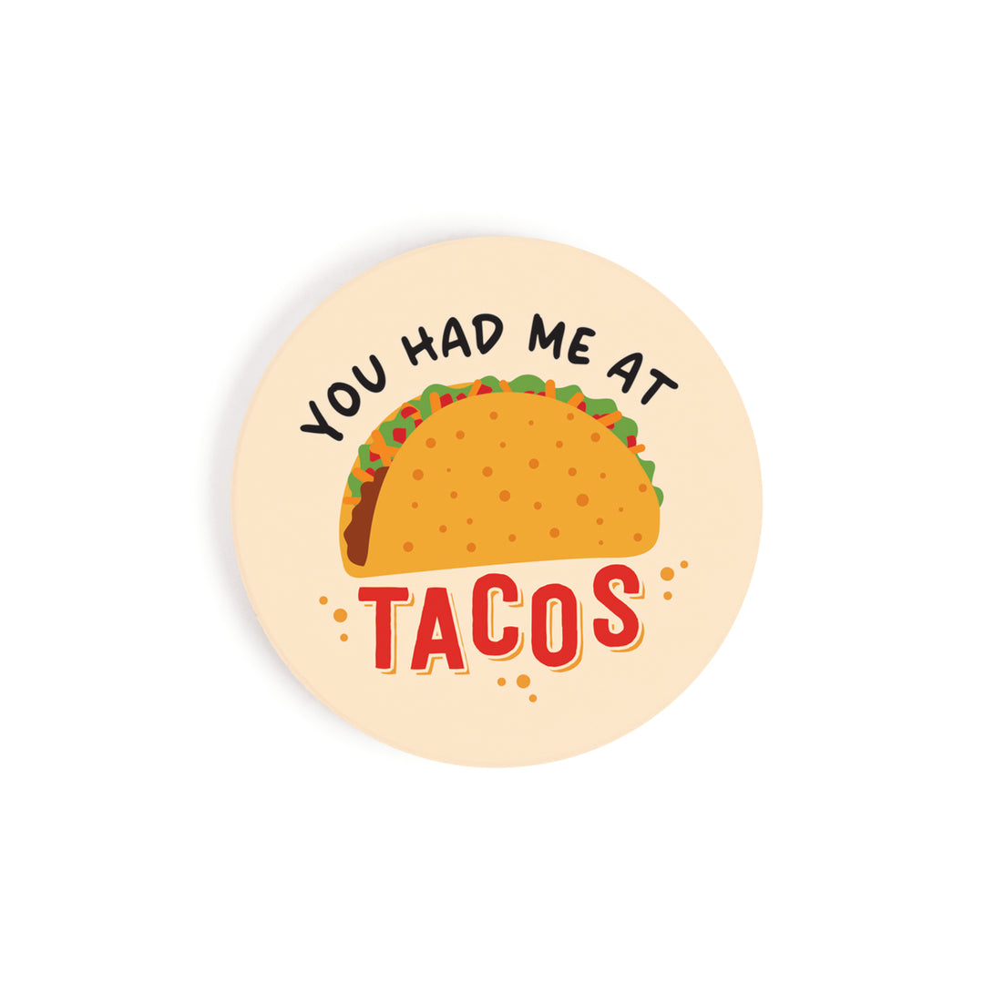 A circular car coaster with an image of a taco and 'you had me at tacos' on it, on a white background.