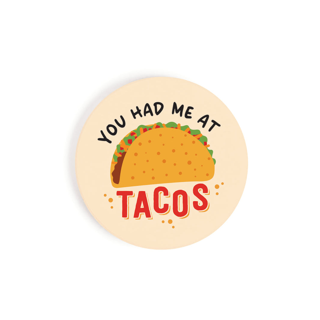 A circular car coaster with an image of a taco and 'you had me at tacos' on it, on a white background.