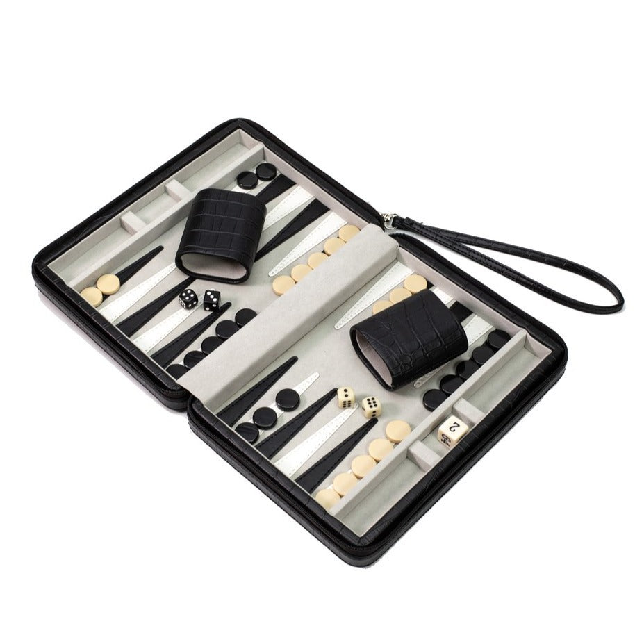 A travel backgammon set with a black faux crocodile case, including dice, cups, and playing pieces.