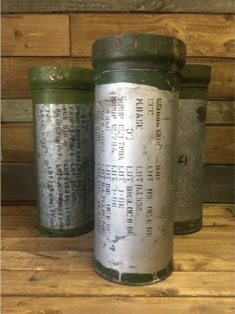 Two vintage metal ammo canisters with green paint, displaying various labels and inscriptions, repurposed as plant stands.