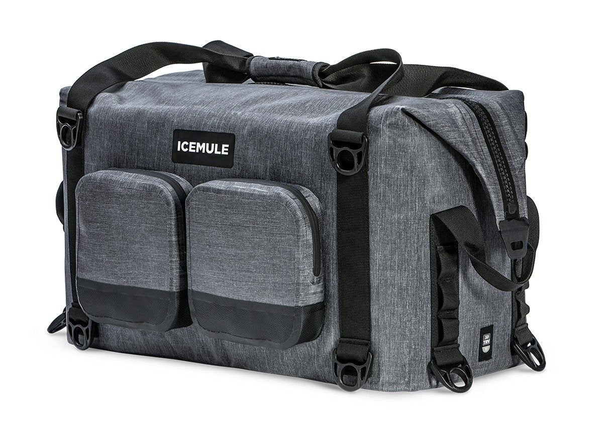 A gray Ice Mule Traveler soft cooler with a black top zipper and side straps, featuring a front pocket and the Ice Mule logo.