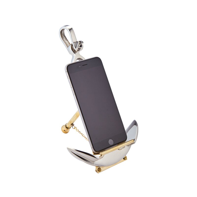 A decorative anchor-shaped stand with gold and silver colors, holding a phone.