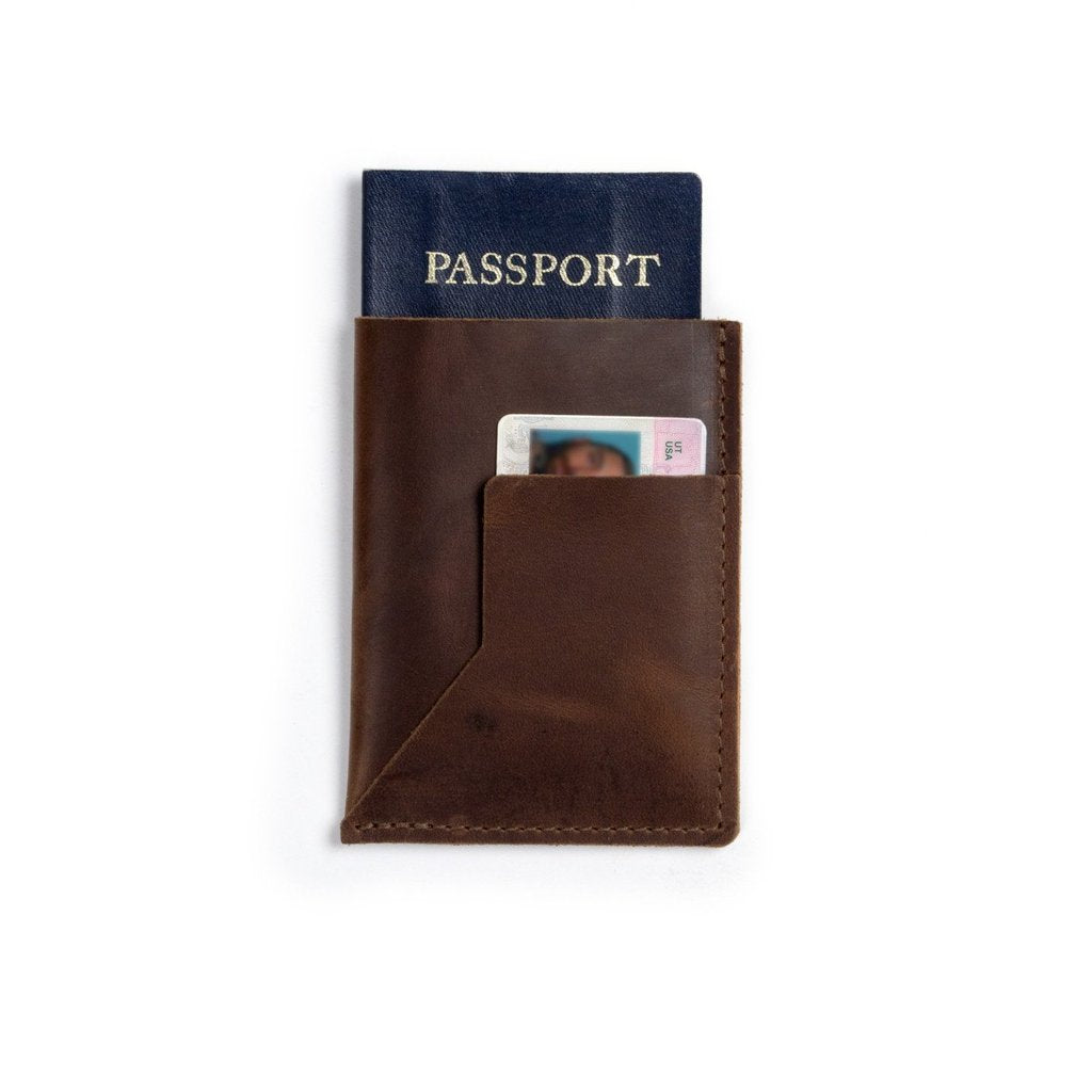 A brown leather passport sleeve with a passport and ID on a white background.