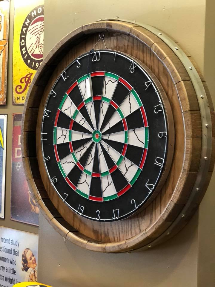 Dartboard made from a whisky barrel hanging on a wall.