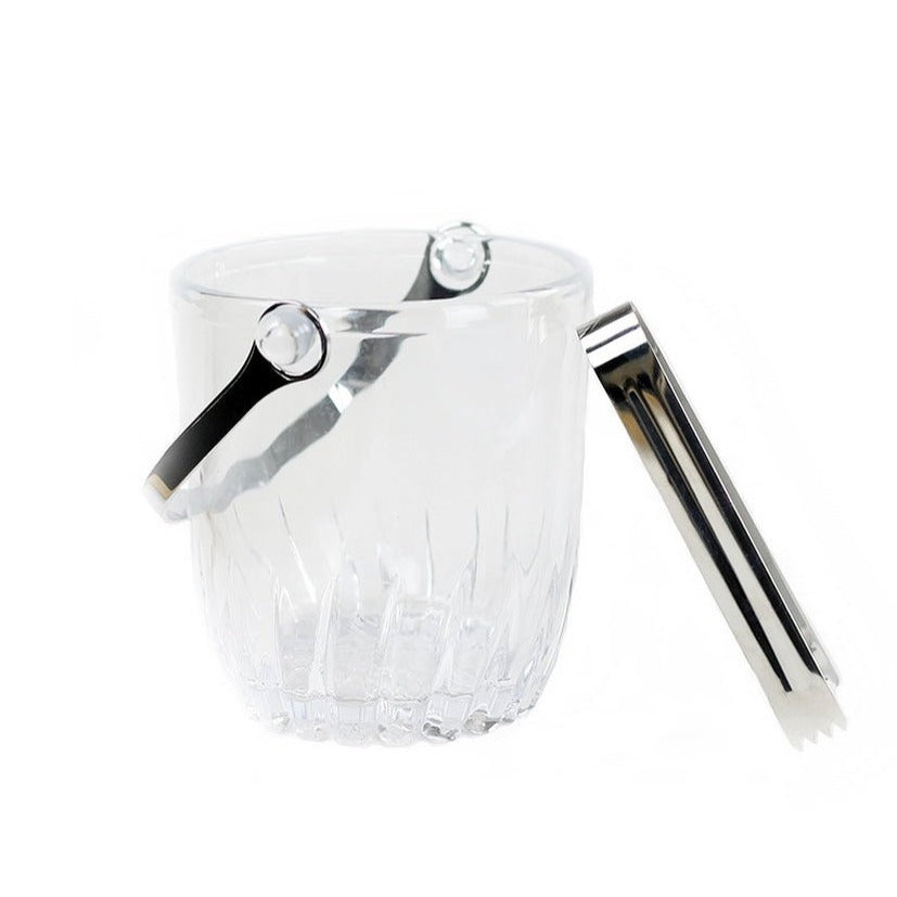 A clear glass ice bucket with a handle and silver tongs.