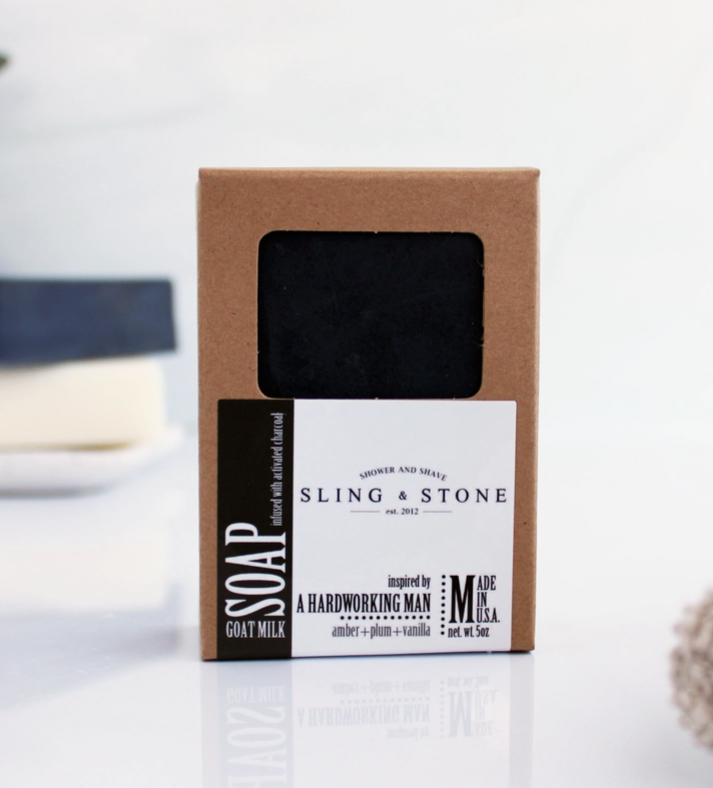 Bar of plum, amber, and vanilla scented goat milk soap in a cardboard box with 'Sling & Stone' branding on a white background