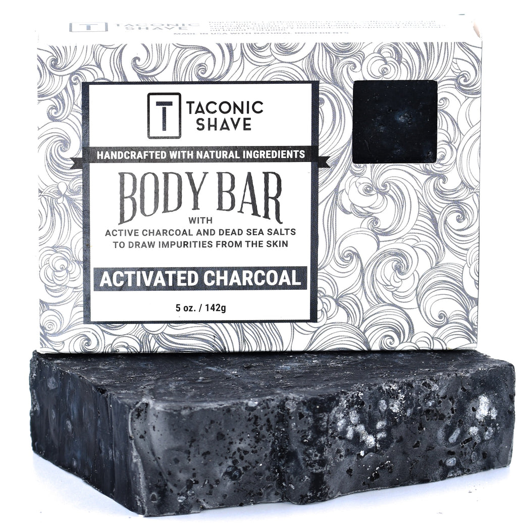 A packaged Taconic Body Soap Bar with activated charcoal, showing the bar of soap and its packaging with a swirl pattern and product information.
