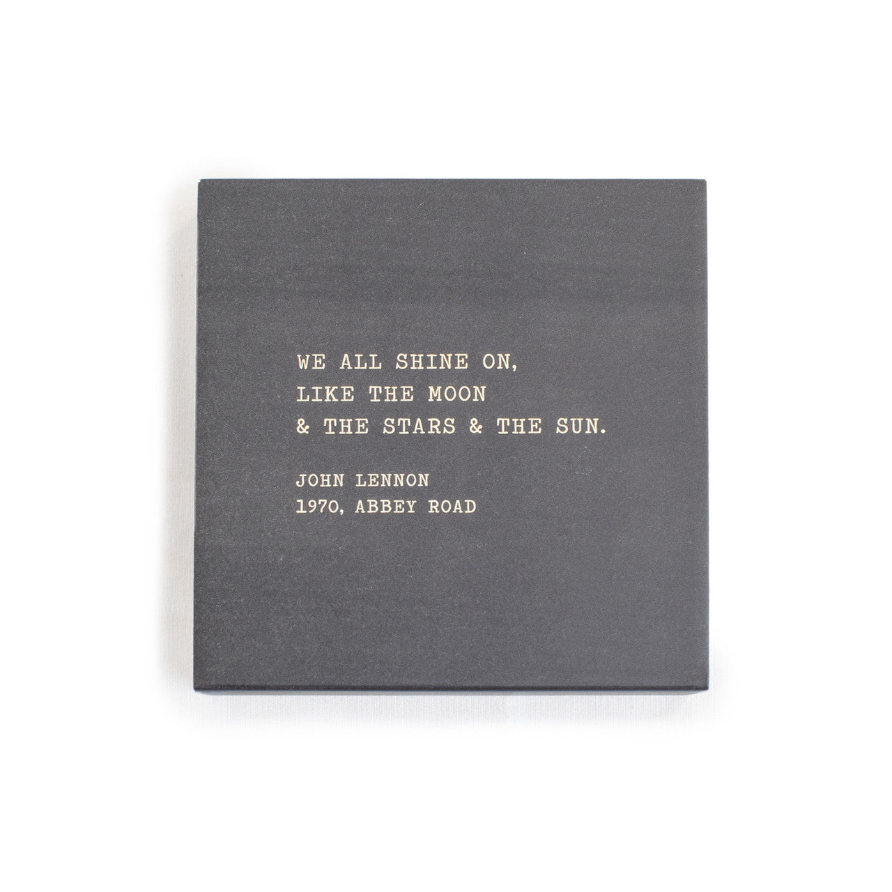 A box of matches with a gray background and a quote by John Lennon written on it.