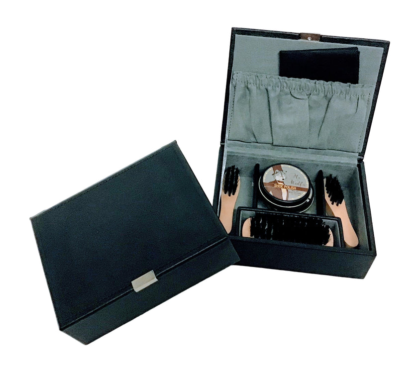 Shoe care kit with a container, brush, and cloths in an open black box beside a closed black box on a white background